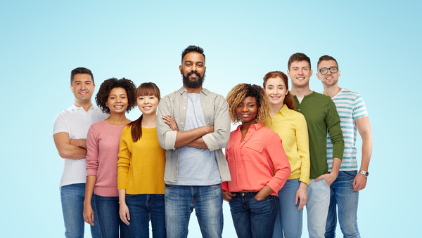 A group of 8 smiling people stood in front of a blue background.